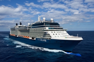close up image of the front of the front of the Celebrity Eclipse cruise ship featuring deep blue seas and blue skies with clouds