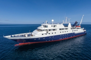 Close up of the Celebrity Xpedition cruise ship featuring the deep blue seas and clear blue skies