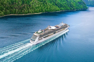 Aerial view of the Serenade of the Seas cruise ship featuring the green forestry in the background and the clear blue waters