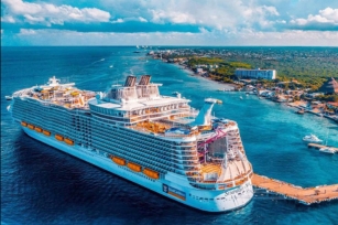 Aerial view of the Symphony of the Seas cruise shipped docked at a port of call featuring a cloudy sky and deep blue waters